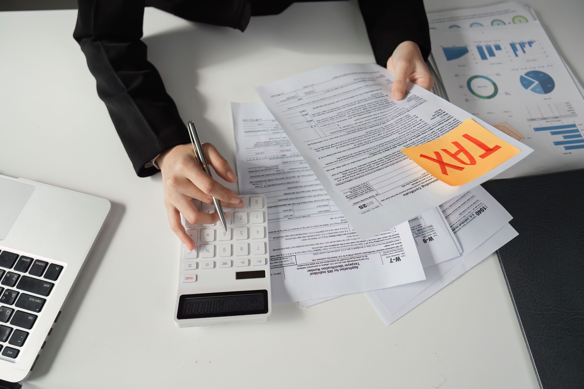 Businesswoman calculating taxes and reviewing financial documents.