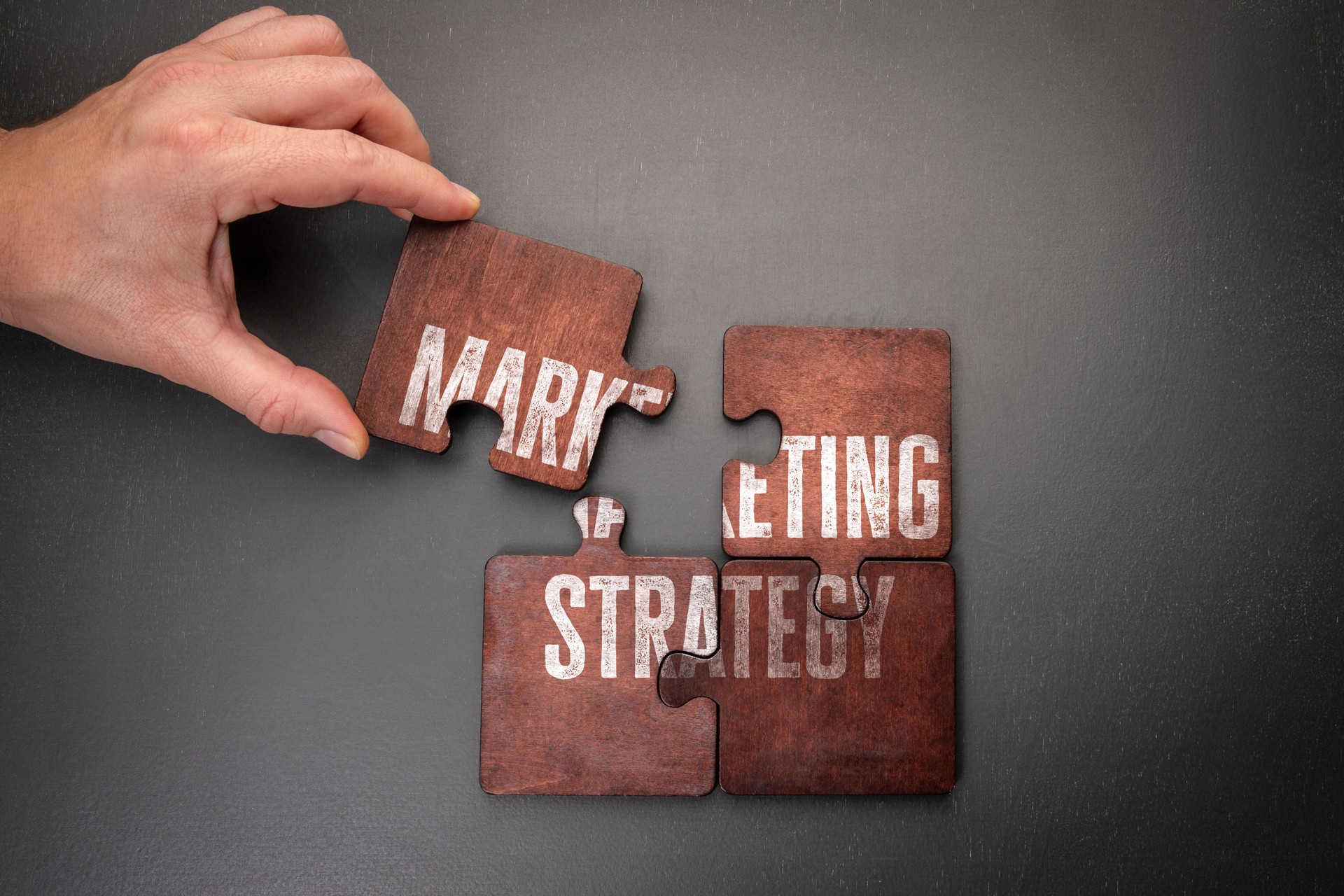 Marketing strategy. Wooden puzzle pieces with text on a dark office table